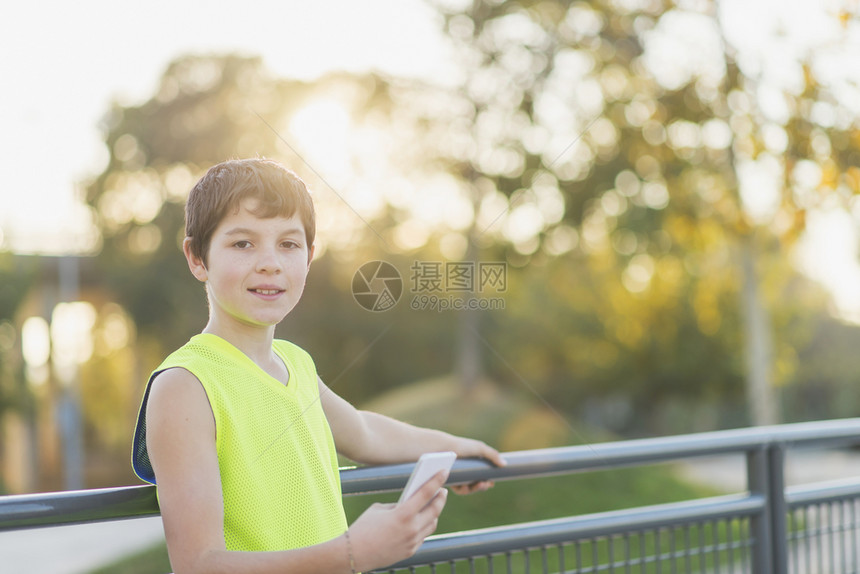 在篮球场上使用智能手机微笑的青少年肖像乐趣应用吸引人的图片