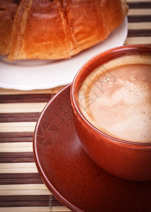 营养烘烤的竹餐巾上新鲜咖啡杯和羊角面包正图片