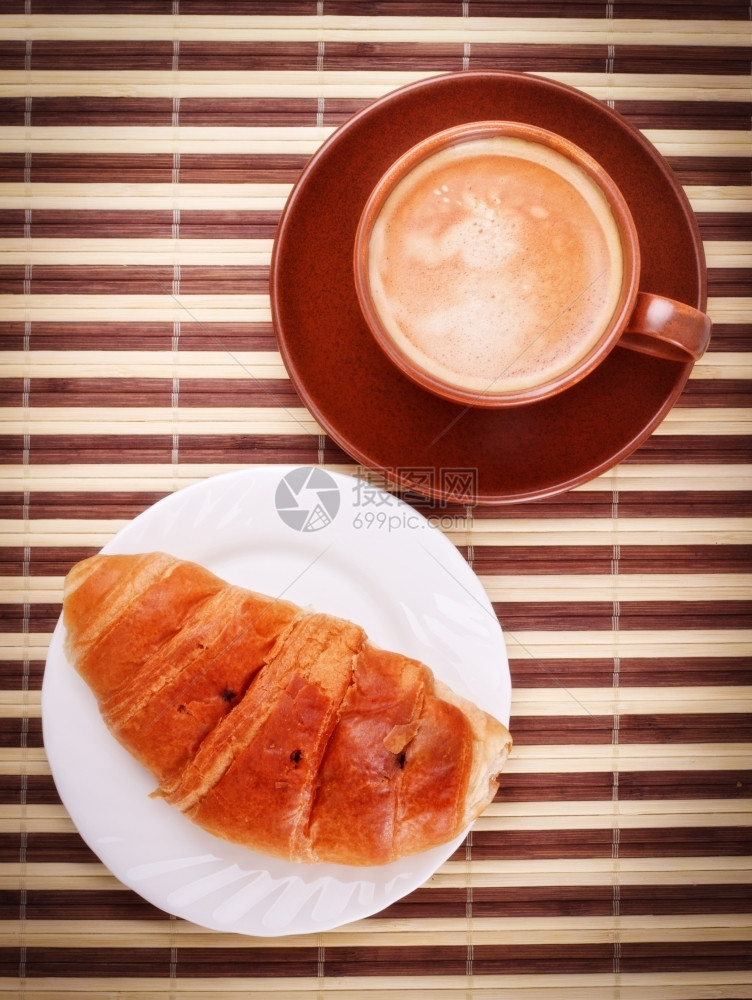 香气竹餐巾上的新鲜咖啡杯和羊角面包泡沫棕色的图片