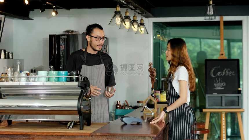 围裙自助餐厅亚洲小企业所有者快乐亚洲男子女咖啡员服务在咖啡店厅柜台的字体上说话女服务员创办新的食品和饮料业男女伙伴关系商界人士概图片