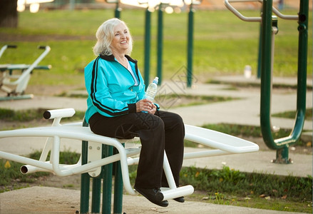 老的70岁健康老年妇女在明秋晚举行的户外锻炼活动后休息肌肉灵活图片