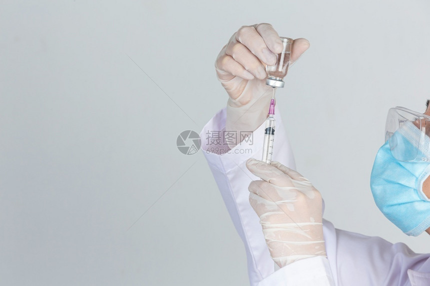 穿戴防护设备手持疫苗注射器的医生图片