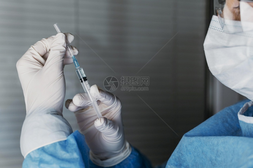 穿戴防护设备手持疫苗注射器的医生图片