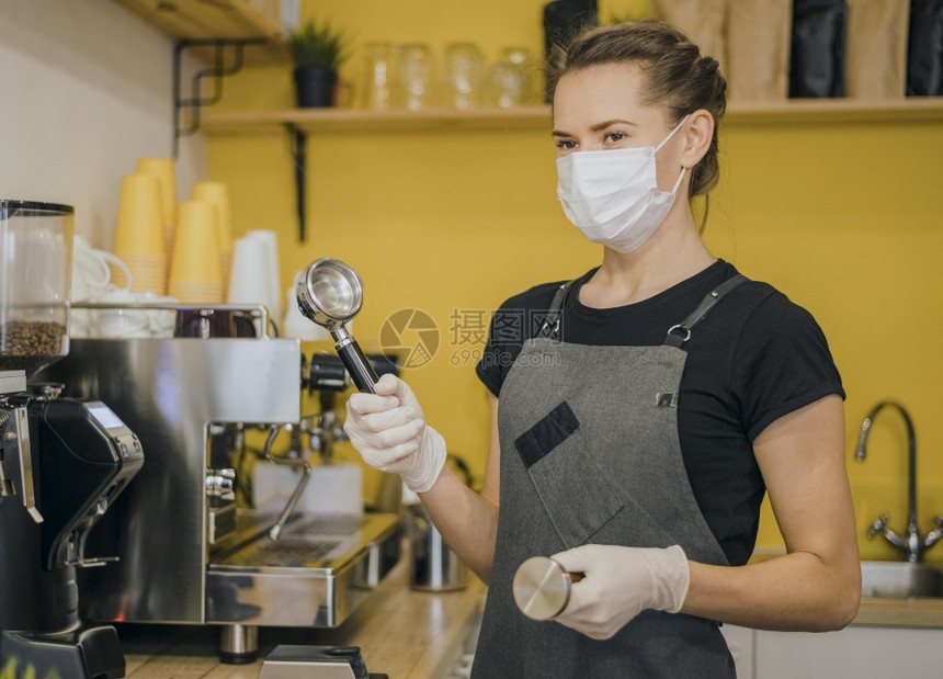 自助餐厅冠状女咖啡师带有准备咖啡机的医学面罩图片