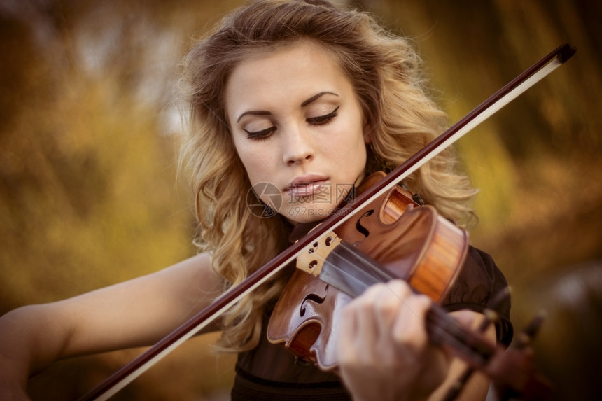 年轻女子在户外演奏小提琴图片