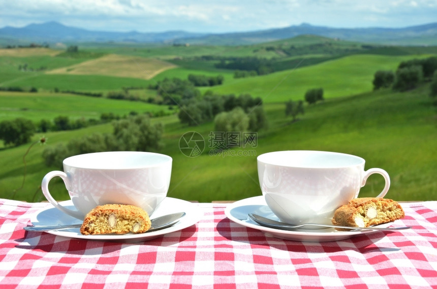 优质的春天曲奇饼意大利Toscan风景对面的桌子上两个咖啡杯和罐头饼干图片
