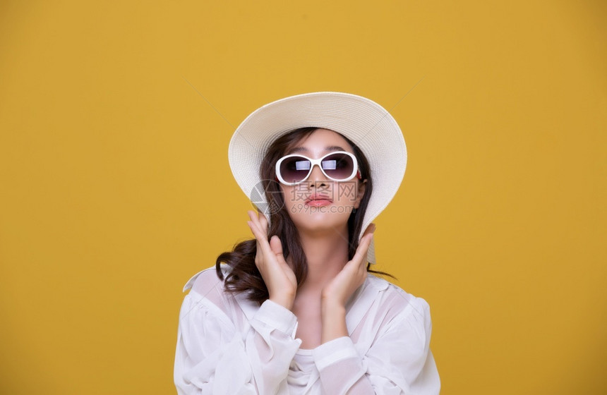女士华丽的可爱亚洲美丽快乐年轻女夏天带着太阳眼镜和帽子笑着欢的夏天看着黄色工作室背景上隔绝的摄影机图片