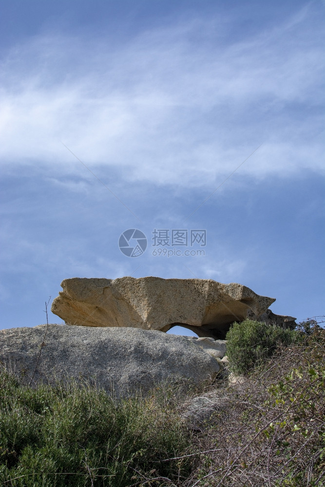 欧洲离奇的天空位于被侵蚀悬崖顶上的花岗岩板在意大利萨丁亚州斯梅拉尔达的CostaSmeralda有蓝天模糊云雾在被侵蚀悬崖顶面的图片