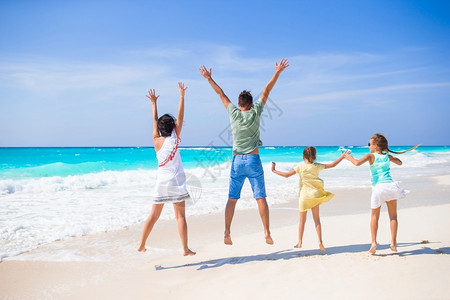 为人父母海滨和孩子在海滩上的在度假年轻家庭玩得开心极了假期图片