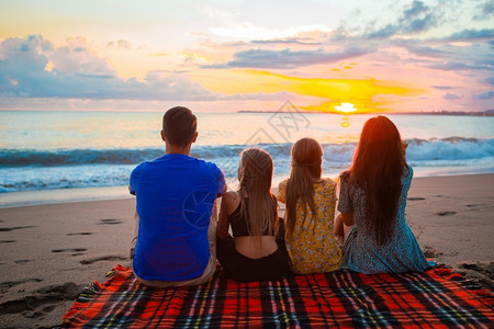 男人日落时在海滩上快乐的美家庭晚上度假的年轻家庭丰富多彩的享受图片