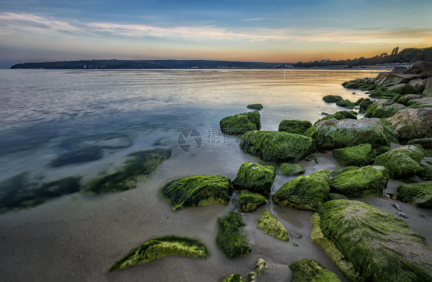 接触美丽的海边岩石岸头上有绿苔丰富多彩的地平线图片