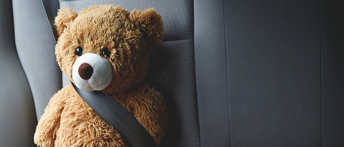 一边戴安全带棕色泰迪熊戴汽车安全带学步的儿童乐趣驾驶背景