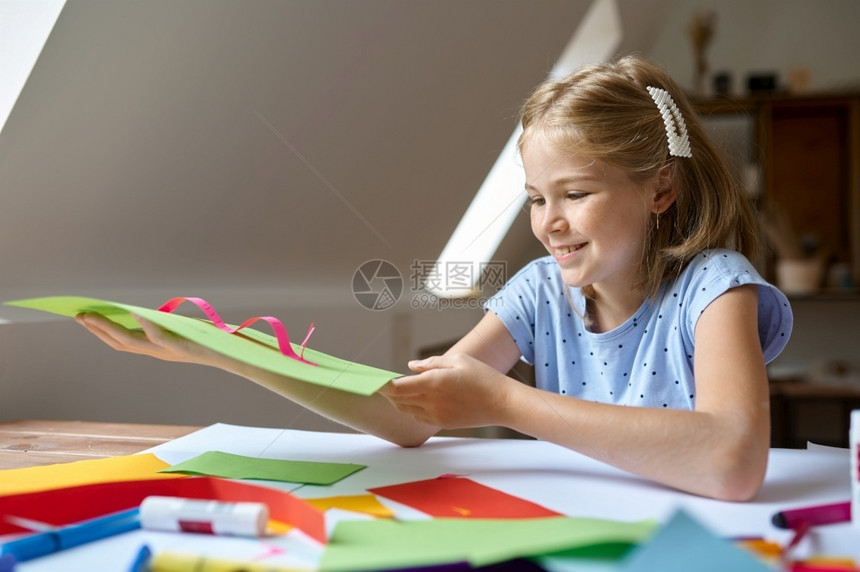 画架学习坐在桌边的小女孩胶水彩色纸在艺术学校上有创意课的小孩年轻画家愉快爱好乐童年幸福表边有彩色纸艺术的图片