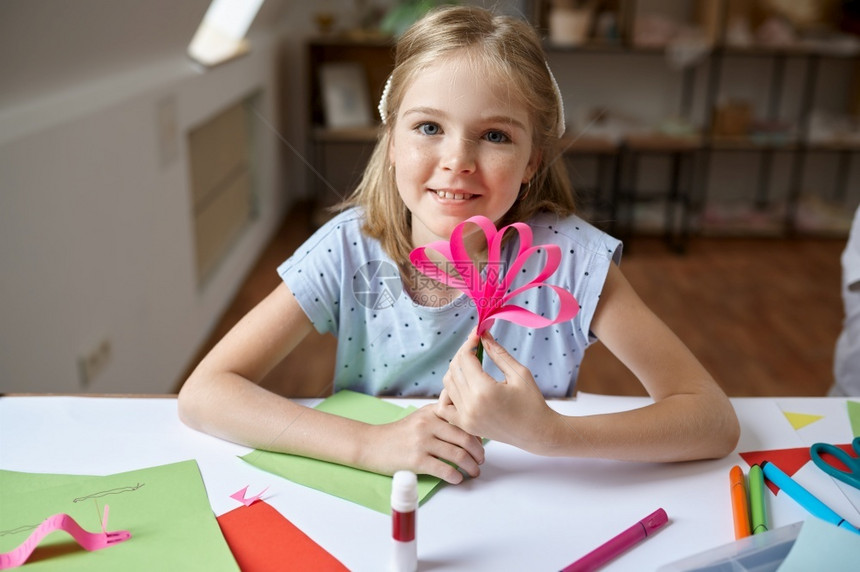 坐在桌边的小女孩胶水彩色纸在艺术学校上有创意课的小孩年轻画家愉快爱好乐童年幸福表边有彩色纸刷子oopicapi手图片