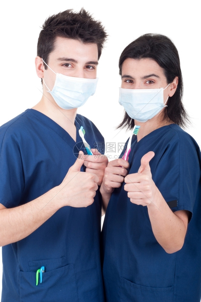 护士男人由友好的牙医队持有刷和在白色背景上被孤立的拇指标志显示医生组成友好牙医队持刷的生图片