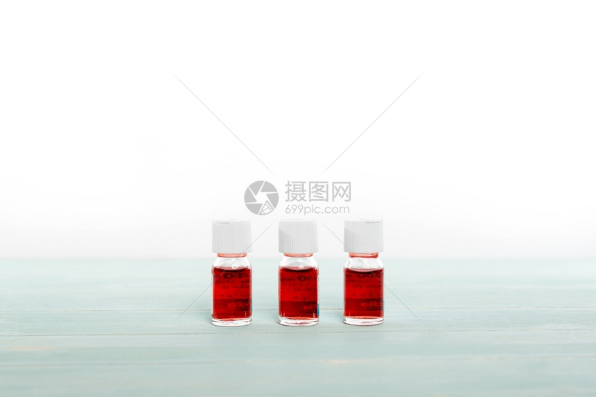 三个装满红色液体的药瓶排成一在白色背景上列疾病小瓶实验室图片