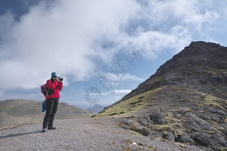 景观令人惊叹的法罗群岛地貌横向景象其背是高山美丽的云层和无法辨识的年轻女徒步者在法罗群岛表面光荣风景中进行图片拍摄Postcar图片