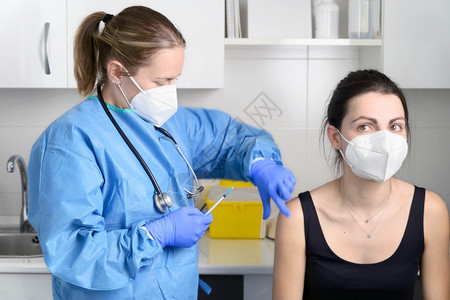 戴防护口罩的女性接种冠状疫苗图片