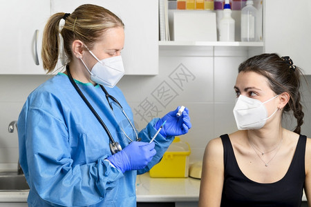 戴防护口罩的年轻女性接种冠状疫苗图片