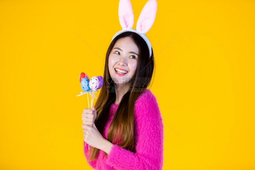 篮子假期复活节的概念快乐笑亚洲年轻女身着兔子耳朵的年轻女手拿着色彩多的复活节鸡蛋扭曲器孤立在黄色空白复制间室背景上庆典图片