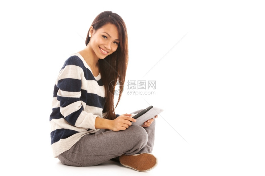 无线的年轻女带着平板电脑的微笑年轻女孩坐在地板上白色孤立的背景之下笑图片