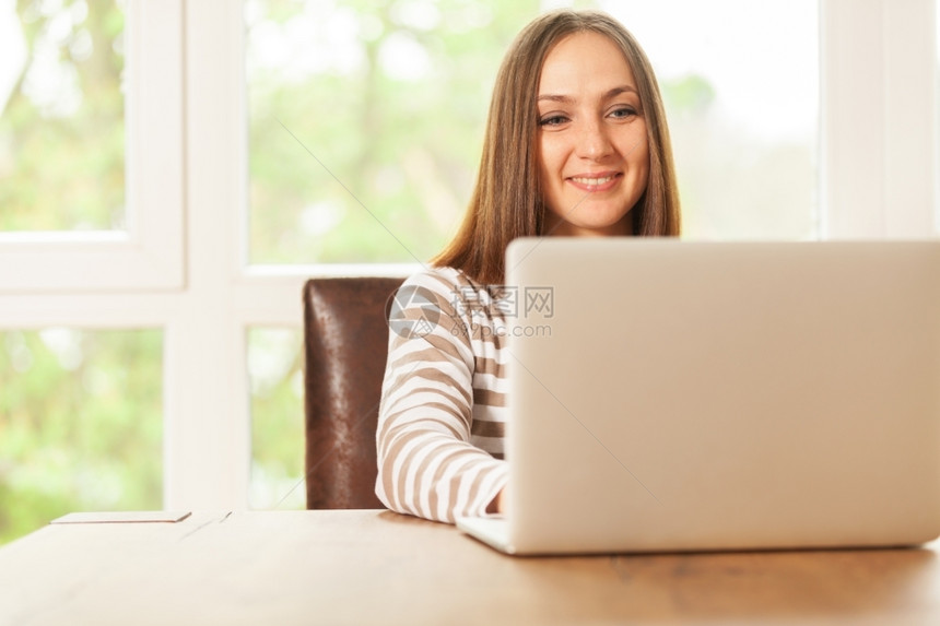 沟通深褐色笑脸女人在家用笔记本工作黑发无线的图片