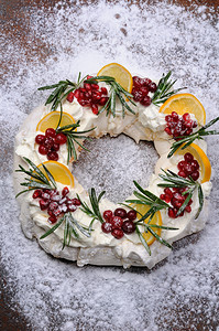 Pavlova蛋糕以圣诞甜圈的形式配奶油石榴红莓玫瑰花香盛宴茶点枝条图片
