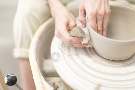 年轻女坐在桌边工作室制造粘土或陶瓷杯劳动者波特图片
