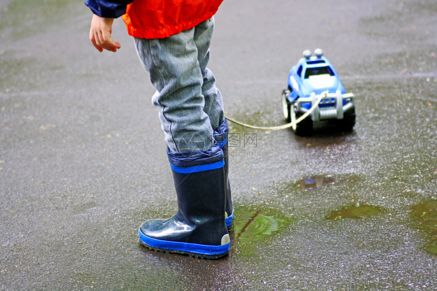 橡胶男孩在水坑里走子手从玩具车的绳子上爬出来肮脏的脚图片