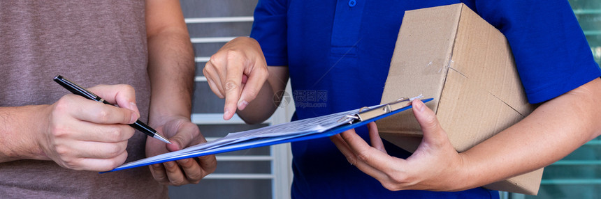 常设地址在确认收到包裹后为客户签署核对清单的蓝色制服托运员交包箱内送货图片