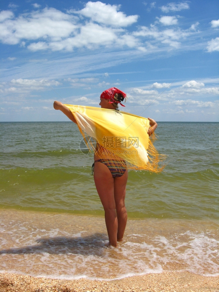 穿着泳衣的女孩站在海边湿的太阳光束图片