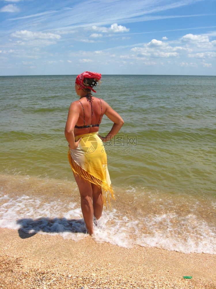 反射穿着泳衣的女孩站在海边手冲浪图片