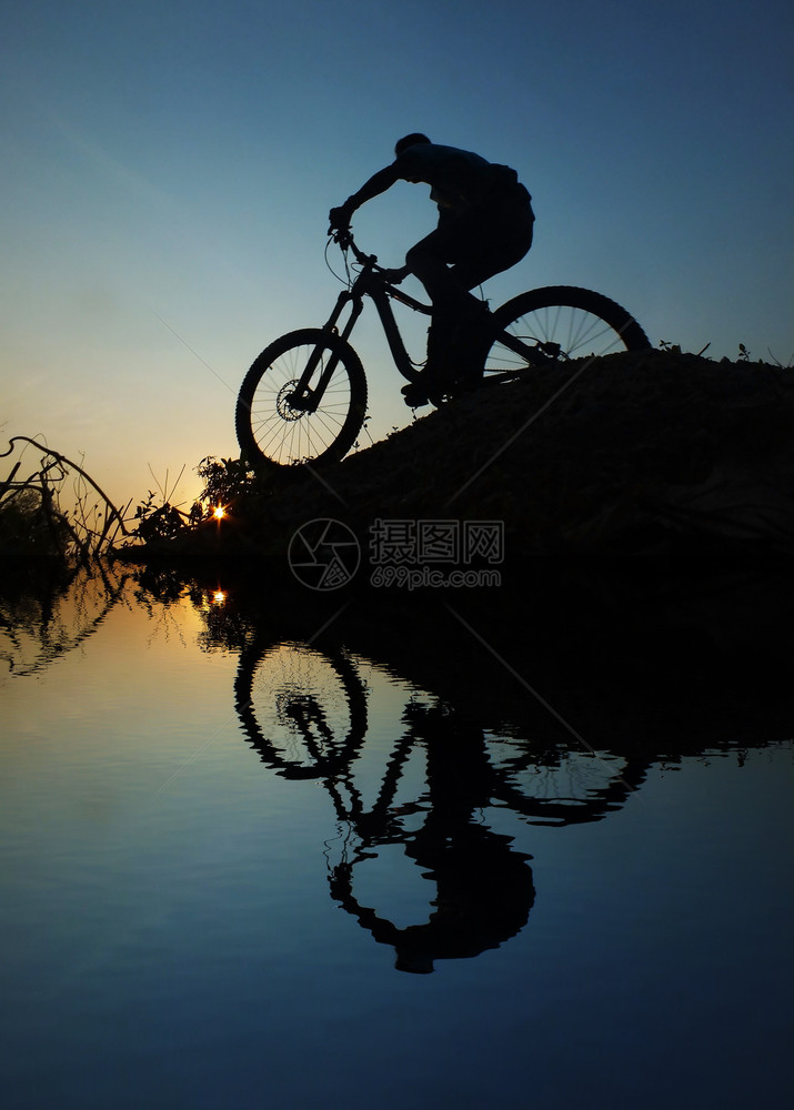 反思一个男人骑着自行车周光日落的河流反射太阳骑自行车的人图片