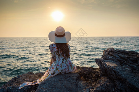西昌泸山坐在岩石顶端的年轻女人看着海边和西昌岛的日落丰富多彩的常设背景