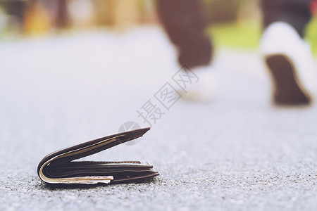麻烦青年男子丢失了皮钱包在街头徒步人行道上的钱财在旅行途中钱袋紧贴地落在路混水泥的人行上钱包具体男人背景图片