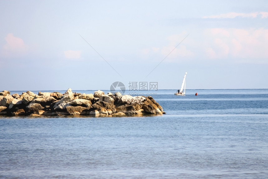 天空绿松石海岸人们在平静的海上乘帆船航行图片