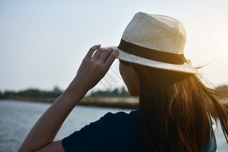美丽那女人穿着白色T恤衫和帽子站在河边双手天空上阳光夏图片