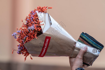 植物群情人节装饰风格手拿着纸上包干橙色鲜花的束图片