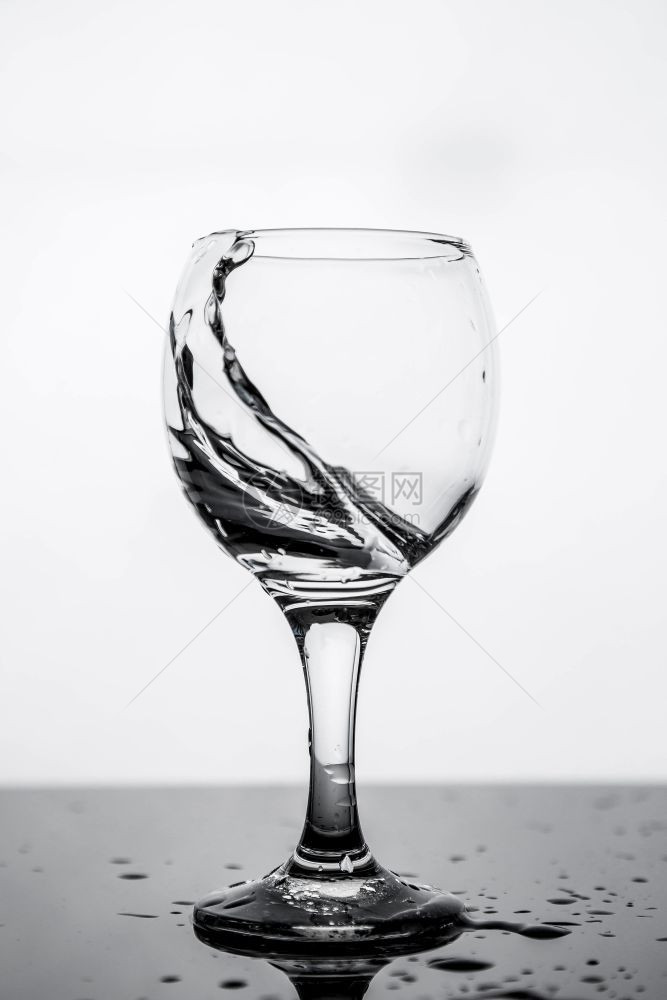 在黑玻璃桌上的一杯清洁饮用水中喷洒花满的桌子健康图片