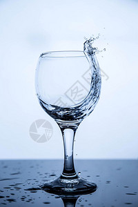 清除涟漪关心在黑玻璃桌上的一杯清洁饮用水中喷洒花图片