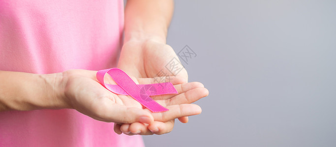 穿粉红T恤的妇女手握粉丝带图片