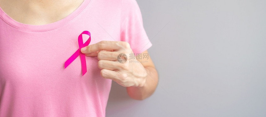 穿粉红T恤的妇女手握粉丝带特写图片