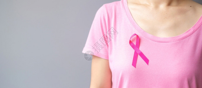 穿粉红T恤的妇女佩戴粉丝带预防癌症概念图片
