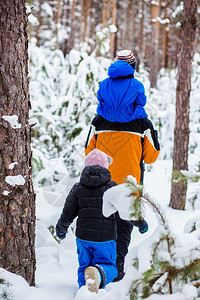森林散步孩子们快乐的他冬天父亲带着年幼的孩子在树林里散步雪地橇和球中的冬季活动背景