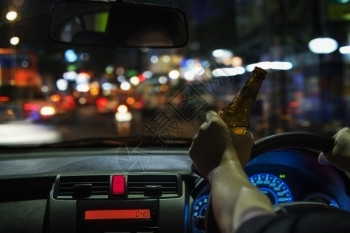 醉罪犯人晚上在城里开车时喝啤酒左手驾驶系统很危险左手驾驶系统违反背景图片