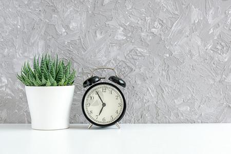 时间生活最后期限黑色闹钟和绿多肉植物放在灰色混凝土墙背景的桌子上白色锅早5点到8概念早上好复制空间图片