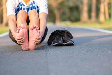 后脚跟男人活动亚洲在训练裔运动员在上午和健康概念外跑步和锻炼后脚有单手疼痛和问题身着运动腿部受伤肌肉疼痛的年轻健身壮男子在训练亚裔跑者背景