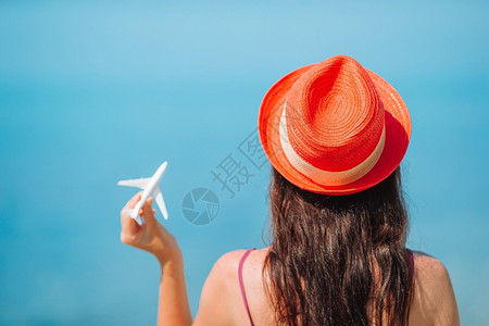 现代的岛商业蓝天空背景一架飞机白色微型化后视镜妇女背影旅行概念女手中的微型玩具飞机Trip由飞机牵引旅行和游的概念图象背景图片
