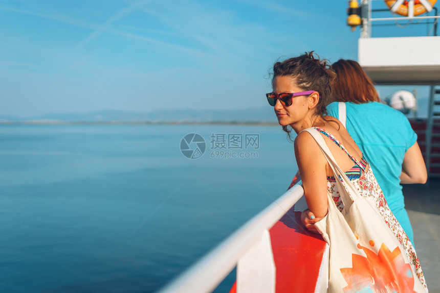 旅游水真实的在阳光明媚假期里身穿夏装旅行看着地平线目的戴太阳眼镜的年轻女子站在船甲上或渡轮的后视镜图片
