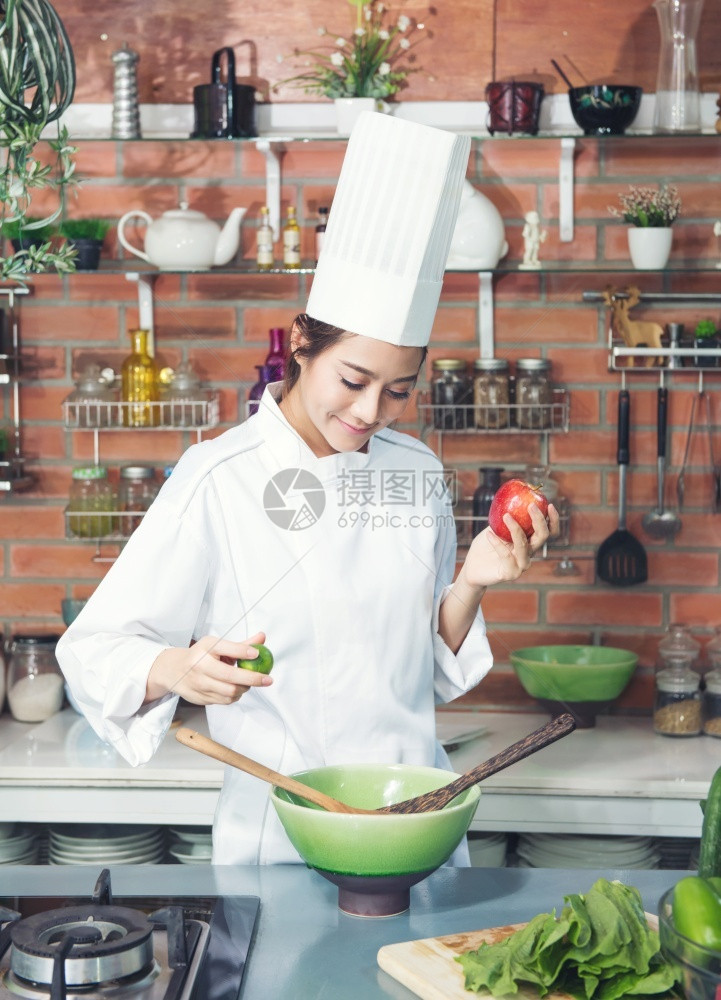 女厨师黑发白西装制服苹果和柠檬在厨房准备烹饪健康食品菜盘上的蔬绿碗行业人们家图片